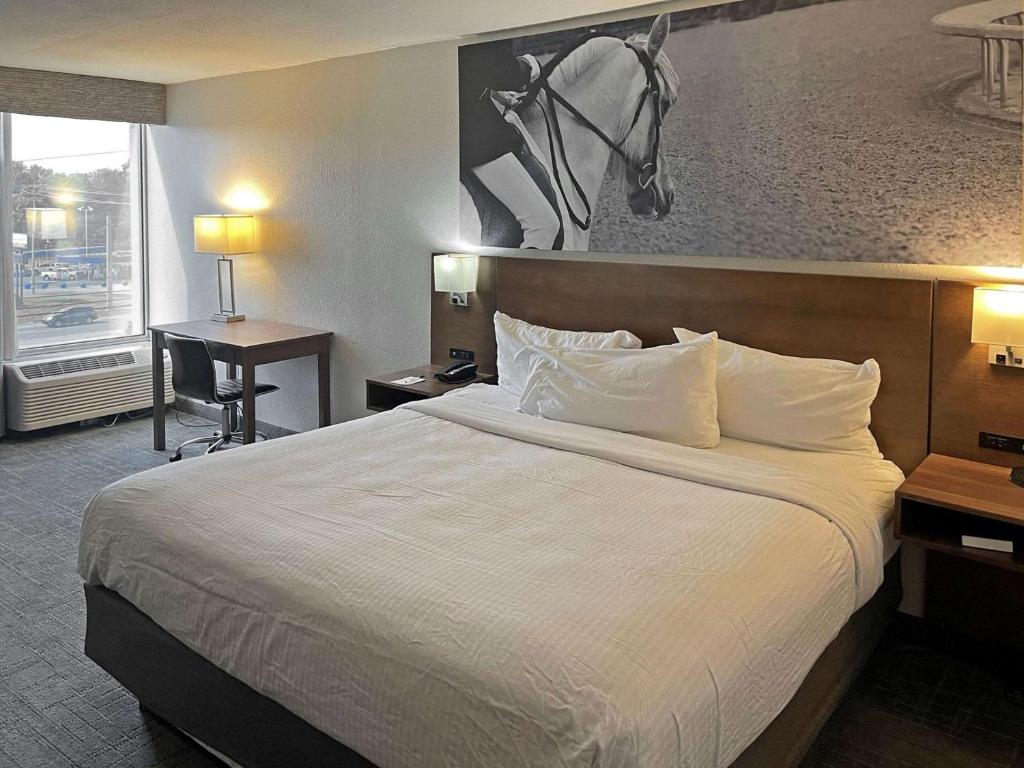 a hotel room with a bed with a horse picture on the wall at Clarion Pointe Hopkinsville near The Bruce Convention Center in Hopkinsville