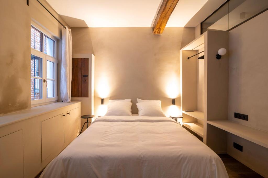 1 dormitorio con 1 cama con sábanas blancas y ventana en Private en-suite room in the heart of Le Sablon en Bruselas