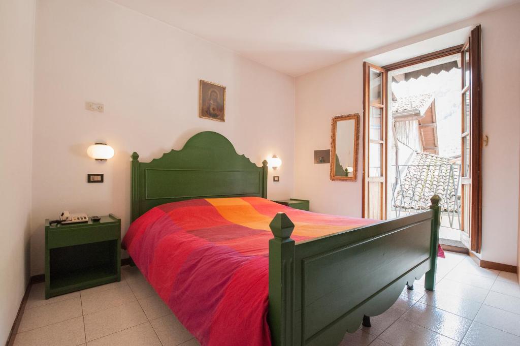 a bedroom with a green bed with a red blanket at Albergo Al Tempo Perduto in Bagolino