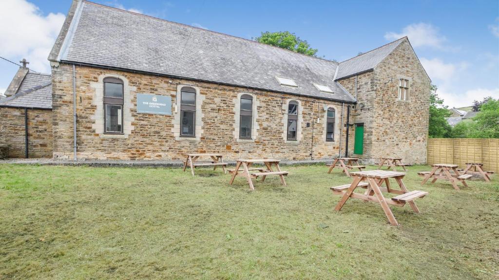 a group of picnic tables in front of a brick building at Greenhead Hostel in Greenhead