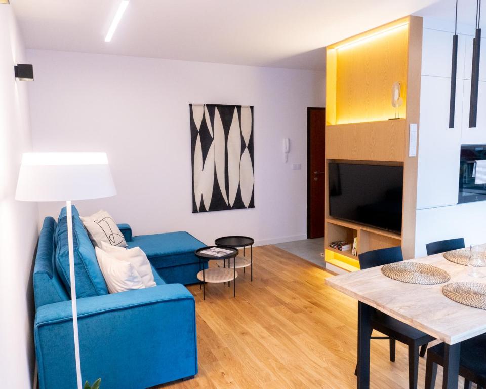 a living room with a blue couch and a table at Hello!Apartments Przy Arkadii in Warsaw