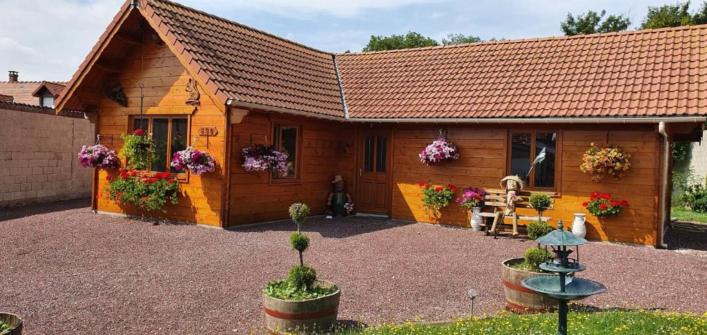 a wooden cabin with flowers in front of it at Le chalet in Saint-Quentin-Lamotte-Croix-au-Bailly