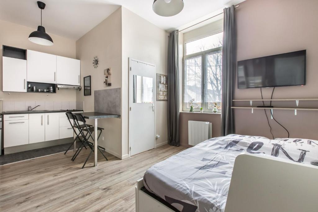 een slaapkamer met een bed en een keuken bij studio Le relax in Roncq