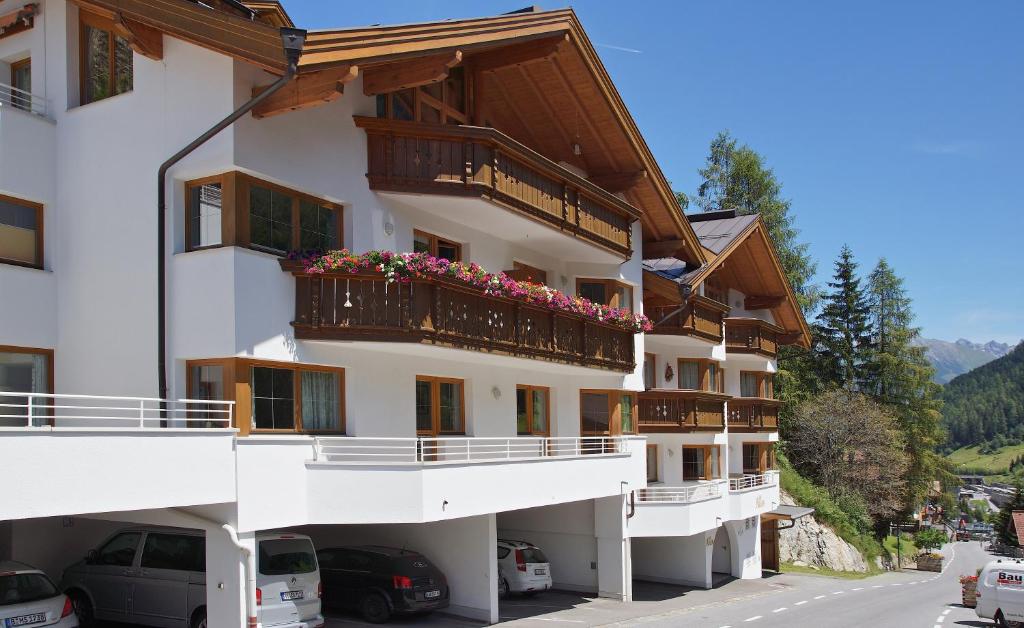 un gran edificio blanco con balcones y flores. en Apart Am Arlen, en Sankt Anton am Arlberg