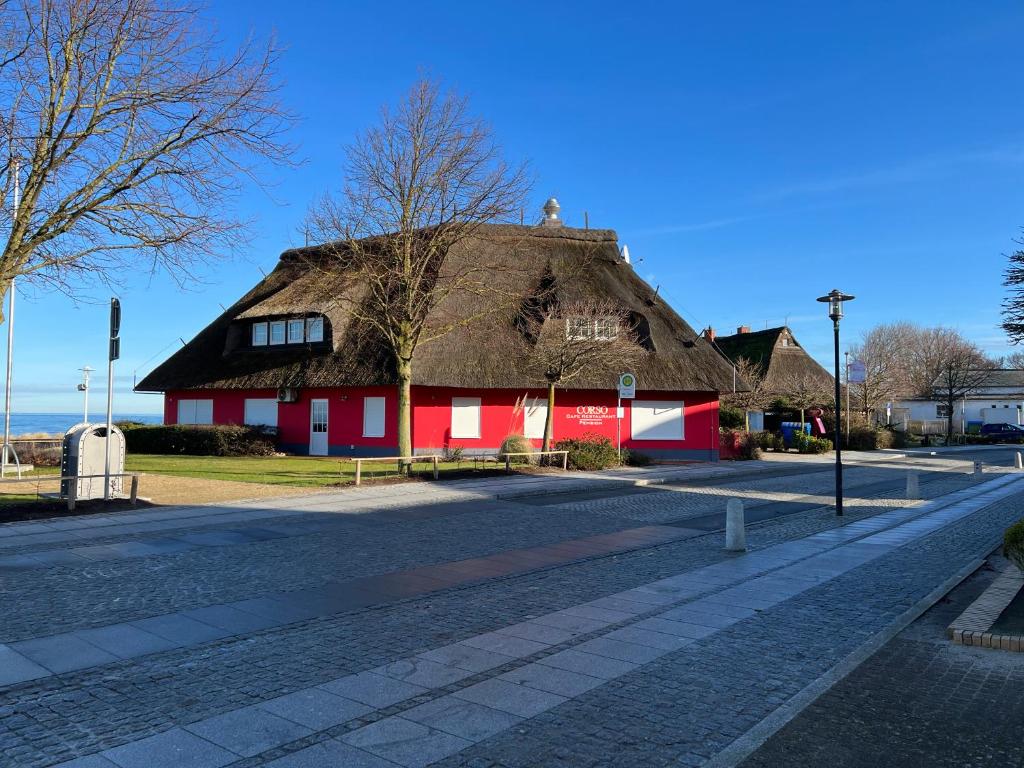 - un bâtiment rouge et blanc avec un toit de chaume dans l'établissement Corso, à Kühlungsborn