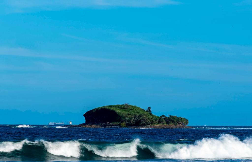 an island in the middle of the ocean with waves at Meraki Villa in Marcoola