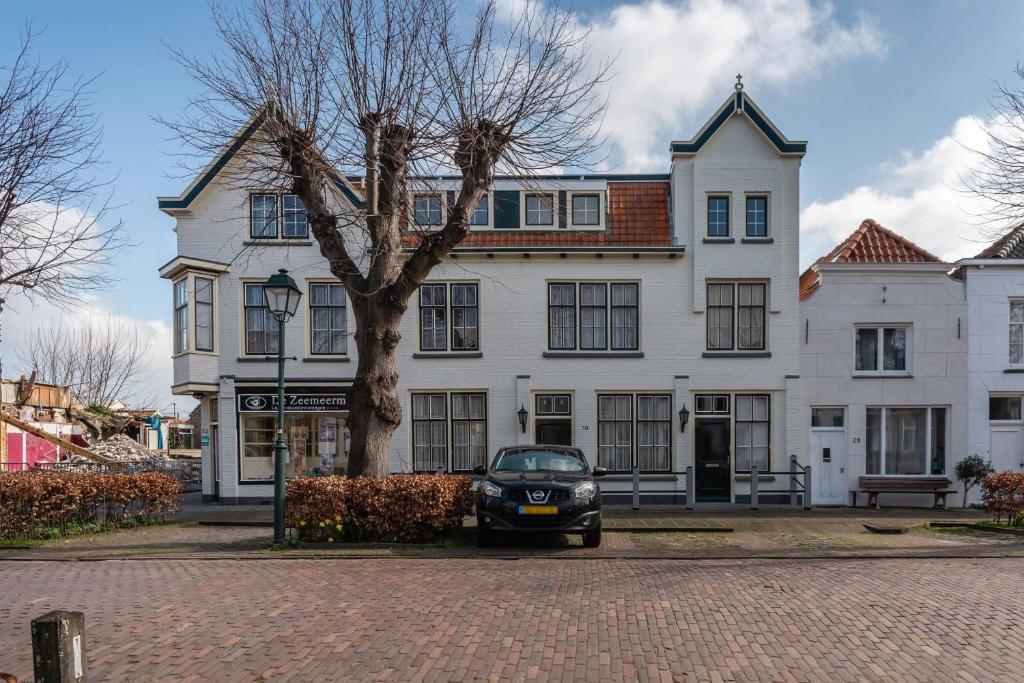 a car parked in front of a large white house at Voorstraat 30 Studio in Colijnsplaat