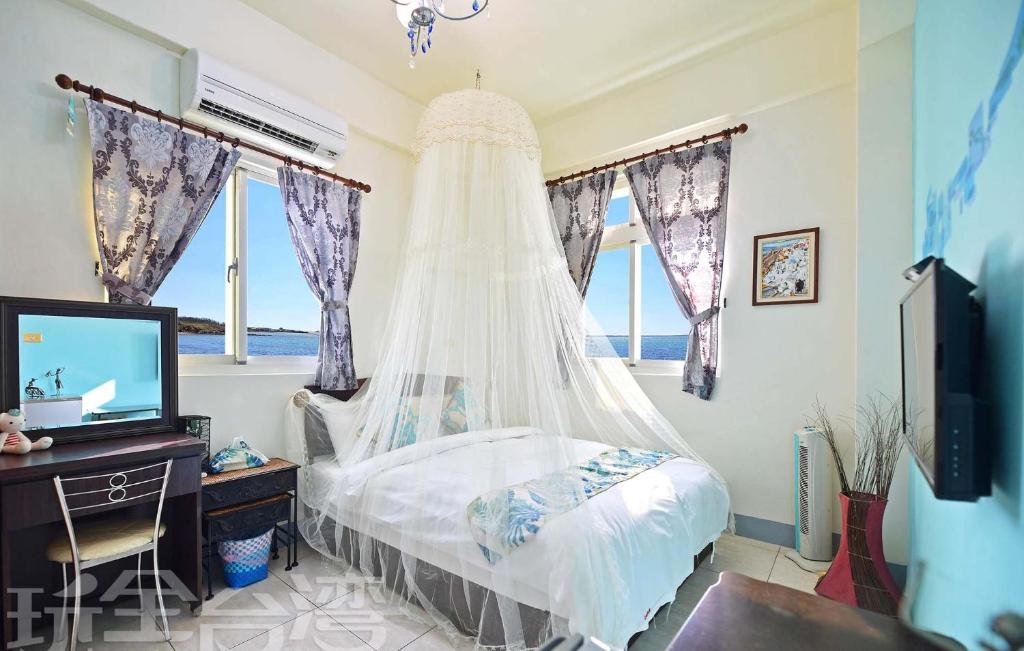 una camera con letto, scrivania e finestre di Yan Hai De Dai B&B a Magong
