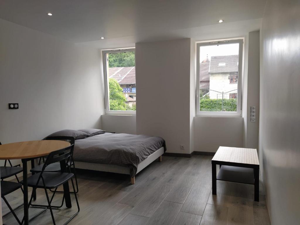 um quarto com uma cama, uma mesa e 2 janelas em Studio 3 em Moirans-en-Montagne