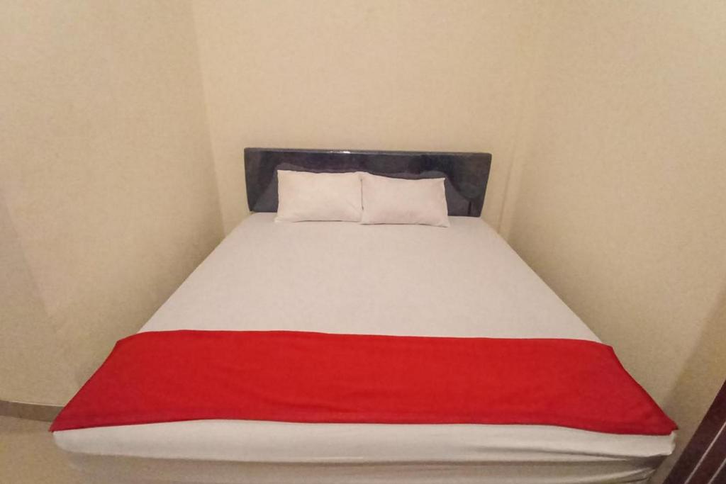 a bed with a red and white blanket on it at RedDoorz Syariah near Sentani City Square in Weversdorp