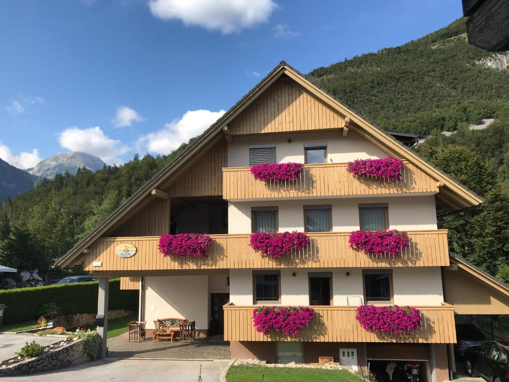 a building with pink flowers on the balconies at Apartments Maja by the river in Bohinj