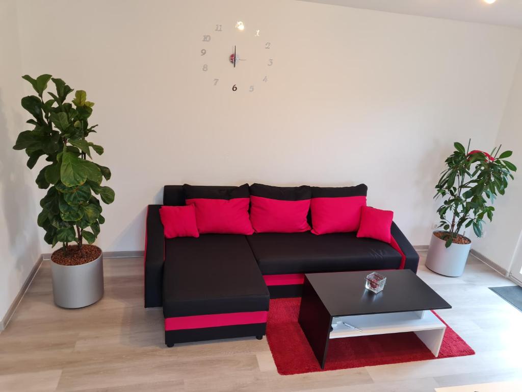 sala de estar con sofá negro y almohadas rosas en Ferienwohnung / Messeunterkunft en Willich