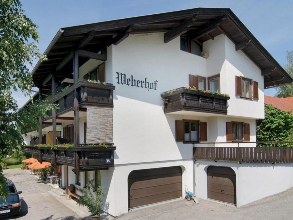 a white building with wooden doors and balconies at Apartments Weberhof in Egg am Faaker See