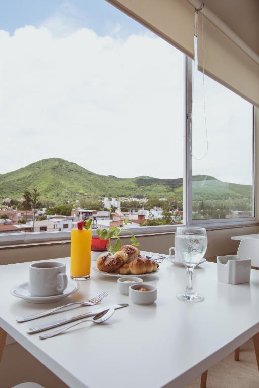 ein weißer Tisch mit einem Teller Essen und einem Fenster in der Unterkunft Hotel Tonight in Salta