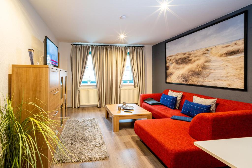 ein Wohnzimmer mit einem roten Sofa und blauen Kissen in der Unterkunft Bördeapartment 1 in Vahldorf