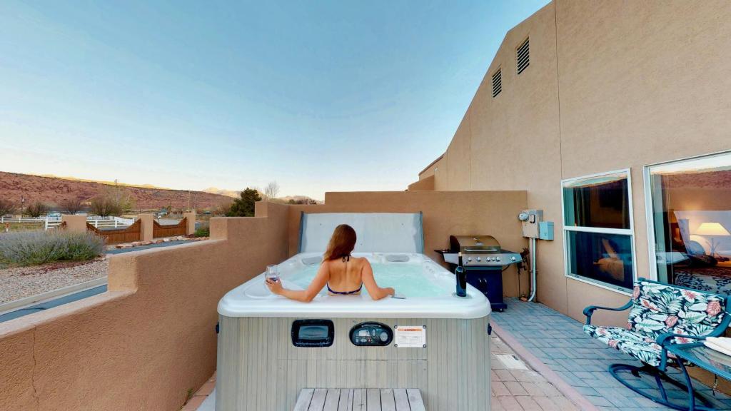 une femme assise dans une baignoire sur un balcon dans l'établissement Arches Abode #A3, à Moab