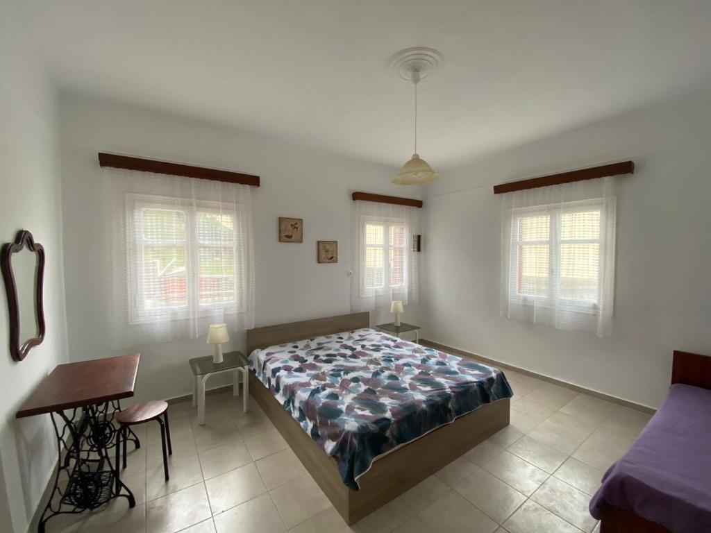 a bedroom with a bed and a table and two windows at Stella's House in Apróvaton