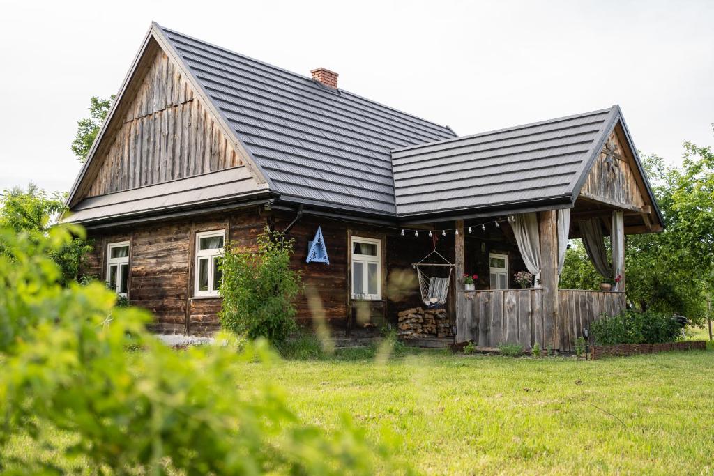a wooden house with a black roof on a field at Chata Latoś in Tocznabiel