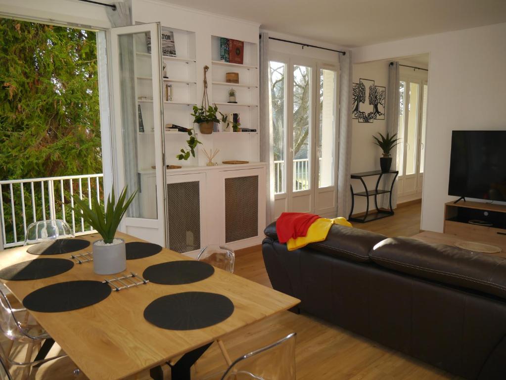 a living room with a couch and a table at Spacieux F5 au parc arboré in Orsay