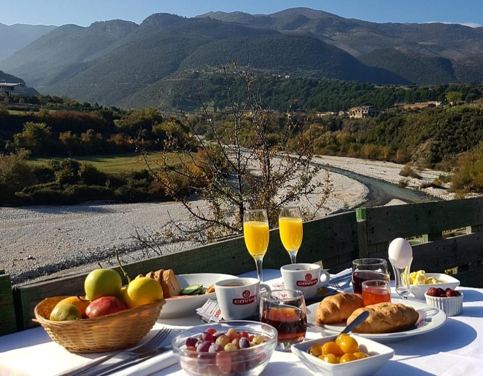a table with food and glasses of wine and a view at Guesthouse Lord Byron in Tepelenë