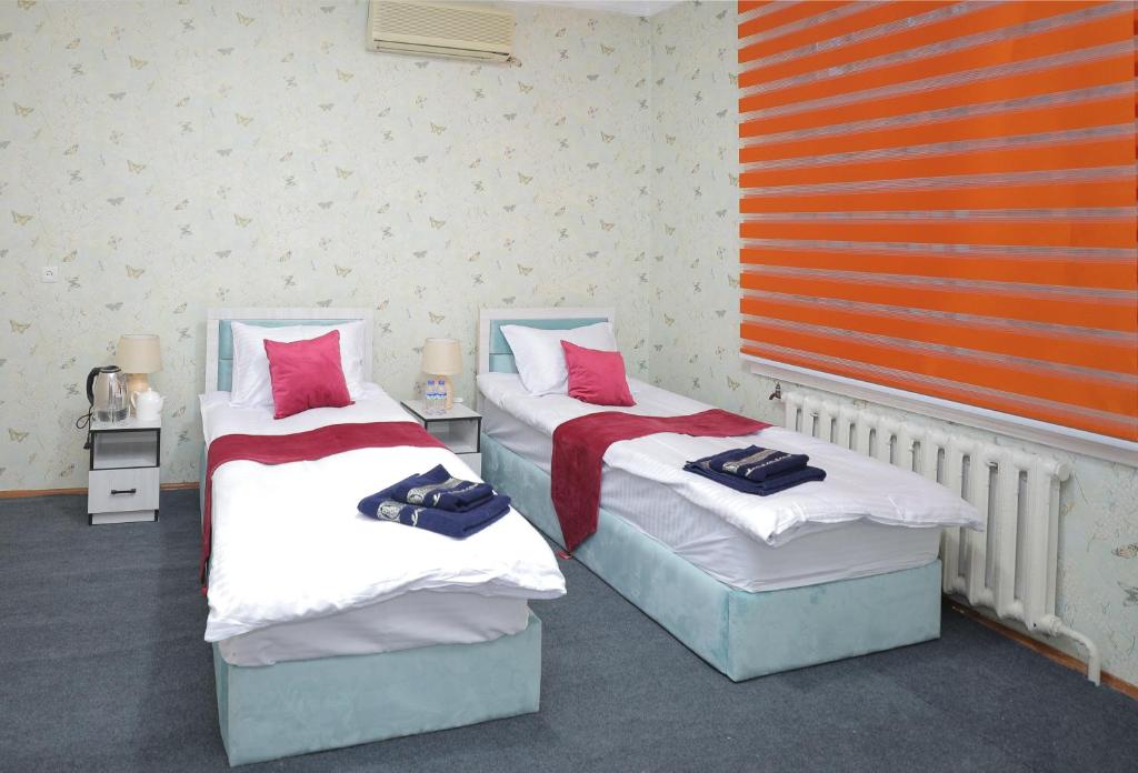 two beds in a room with red and white at Hotel S & D Hostel in Tashkent