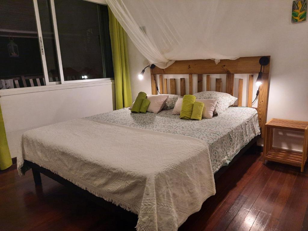 a bedroom with a large bed with green pillows at Villa Kannel in Petit-Bourg