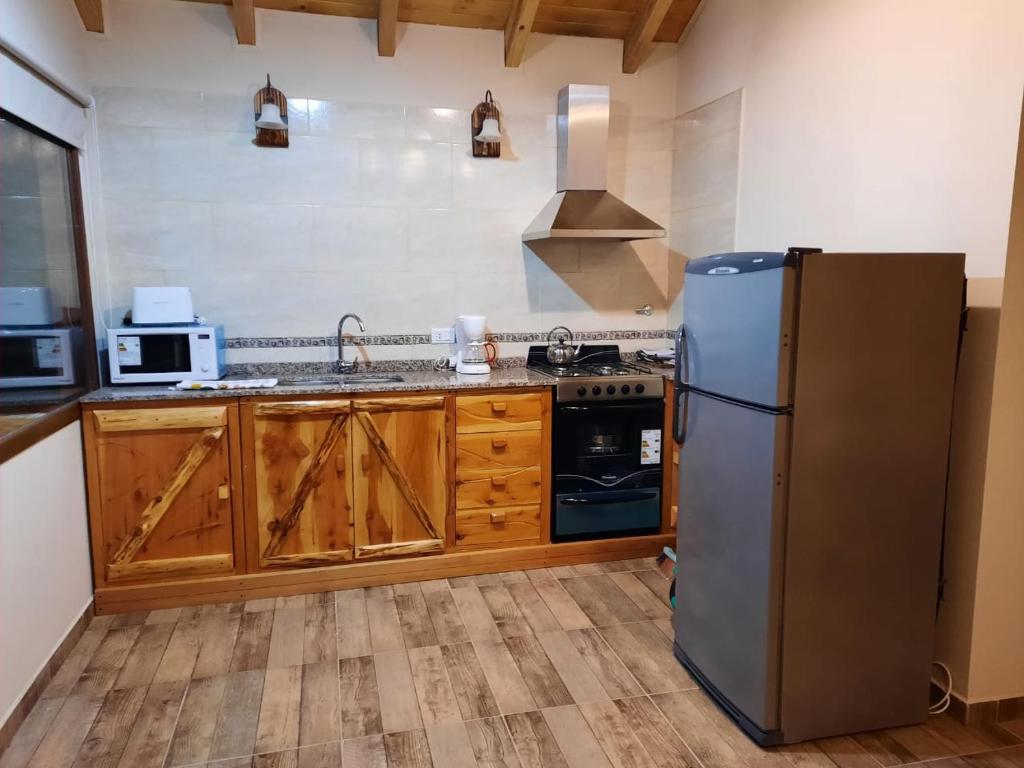 eine Küche mit einem Kühlschrank aus Edelstahl und Holzschränken in der Unterkunft EL SUSURR0 in Villa Pehuenia