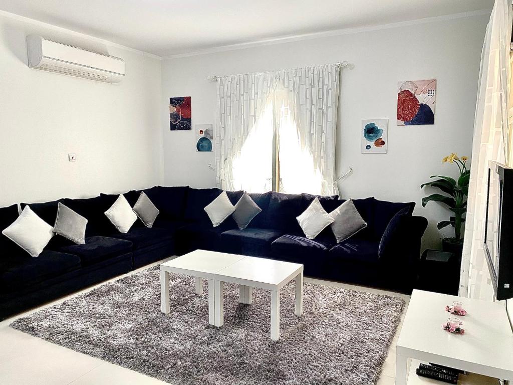 sala de estar con sofá negro y mesa blanca en شقة الواحة روز - Alwaha Rose, en King Abdullah Economic City