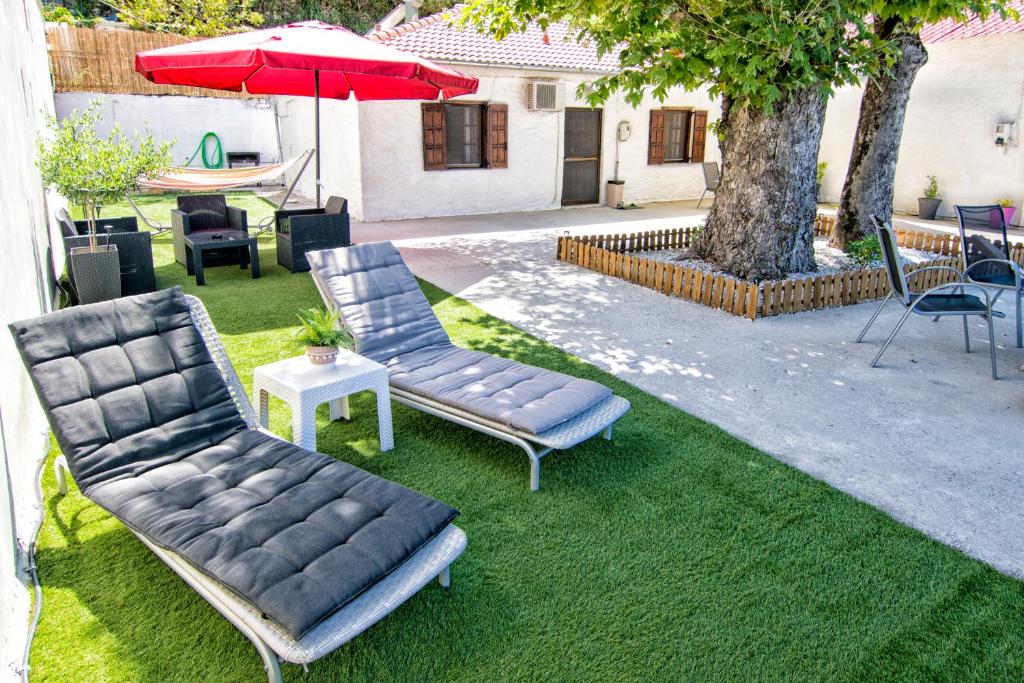 een patio met 2 stoelen, een tafel en een parasol bij Summer House by the Sea in Chorefto