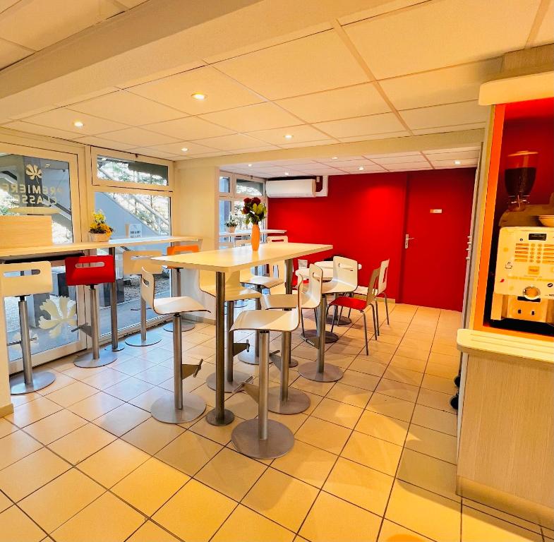 um restaurante com mesas e cadeiras e uma parede vermelha em Premiere Classe St Quentin en Yvelines Elancourt em Trappes