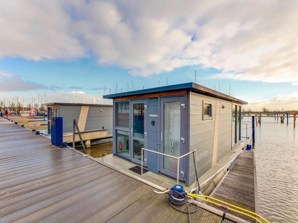 un pequeño edificio en un muelle junto al agua en Modern Houseboat in Marina of Volendam en Volendam