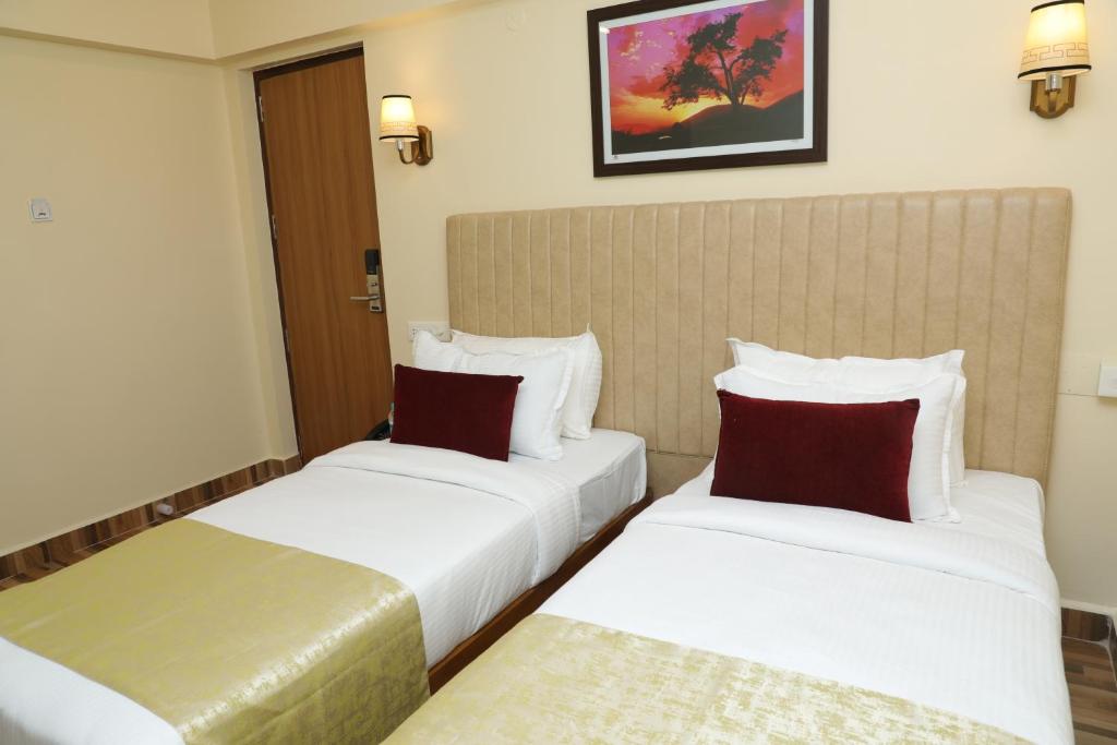 2 camas en una habitación de hotel con almohadas blancas y rojas en Gadiraju Palace Convention Centre & Hotel en Visakhapatnam
