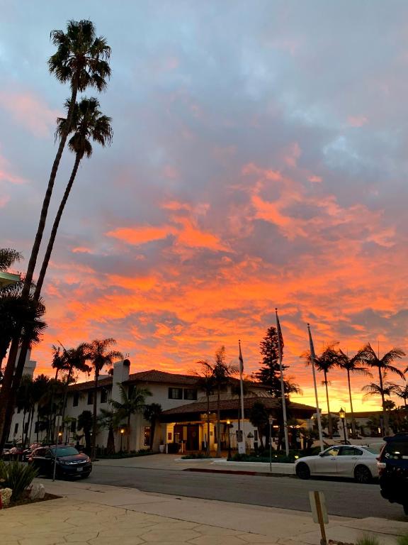 einen Sonnenuntergang mit Palmen und Autos auf einer Straße in der Unterkunft Inn at East Beach in Santa Barbara