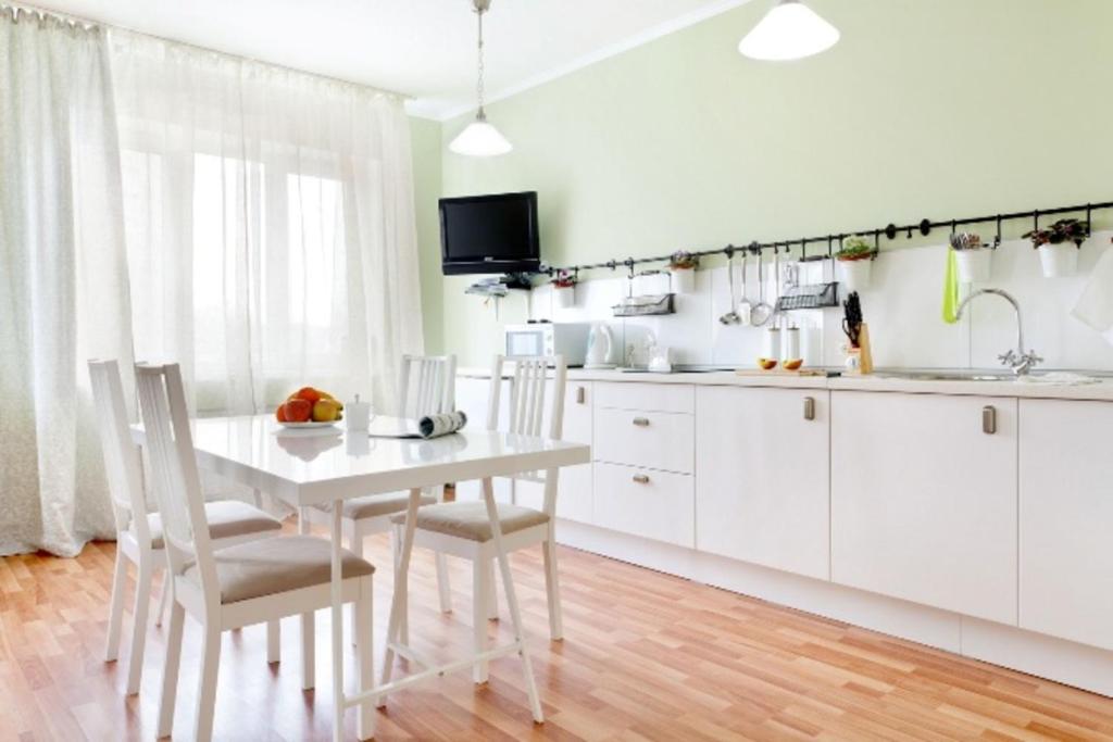 エカテリンブルクにあるEtazhiDaily at Mashinistovの白いキャビネット、白いテーブルと椅子付きのキッチン