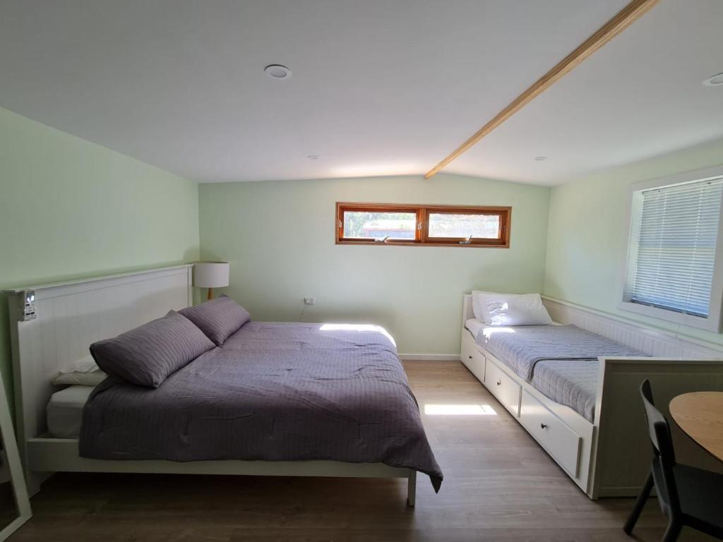 a bedroom with two beds and a table and a window at Sanctuary Cabin in Sanctuary Point