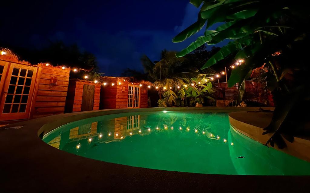 a swimming pool at night with lights around it at Luhme Tulum Hostel in Tulum