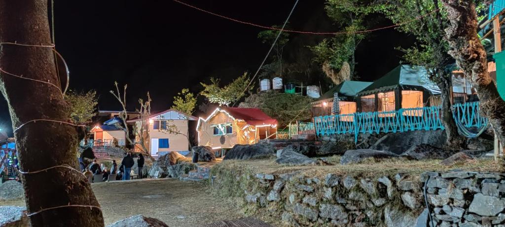 a group of houses at night with lights at The Solitude Camp in Pālampur