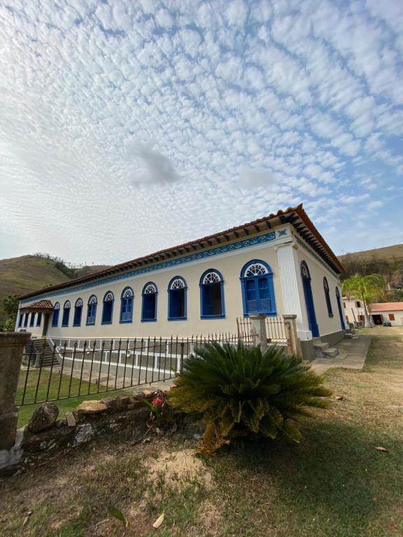 a blue and white house with a fence at Fazenda Penedo in Duas Barras