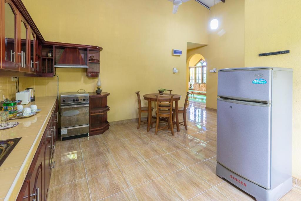 a kitchen with a refrigerator and a table with chairs at Green Villa Apartment in Unawatuna