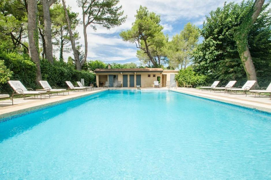 une grande piscine avec des chaises et une maison dans l'établissement Auberge De Noves Domaine Du Deves, à Noves