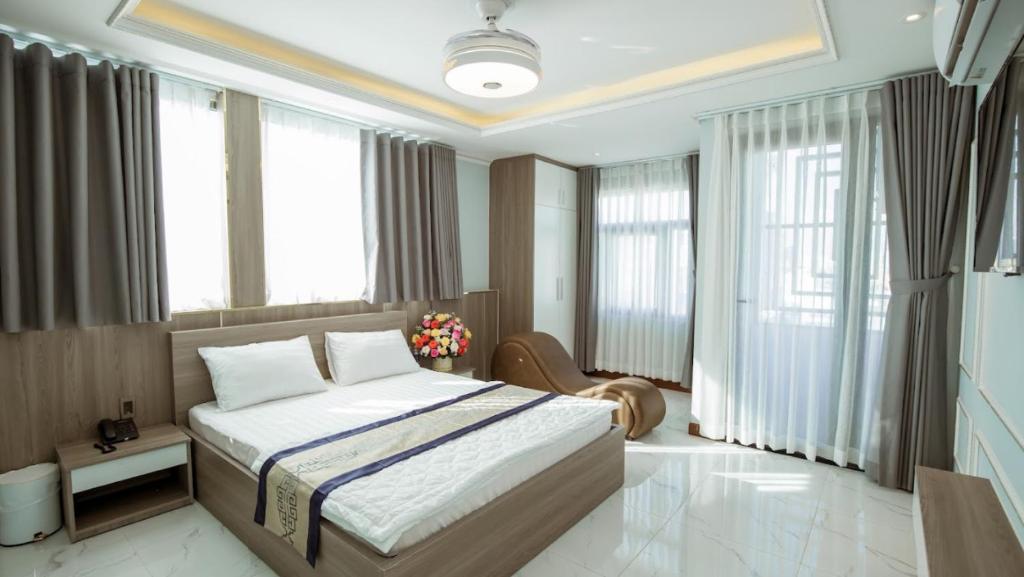 1 dormitorio con 1 cama grande y ventanas grandes en Biển Sao 2 Hotel GV, en Ho Chi Minh