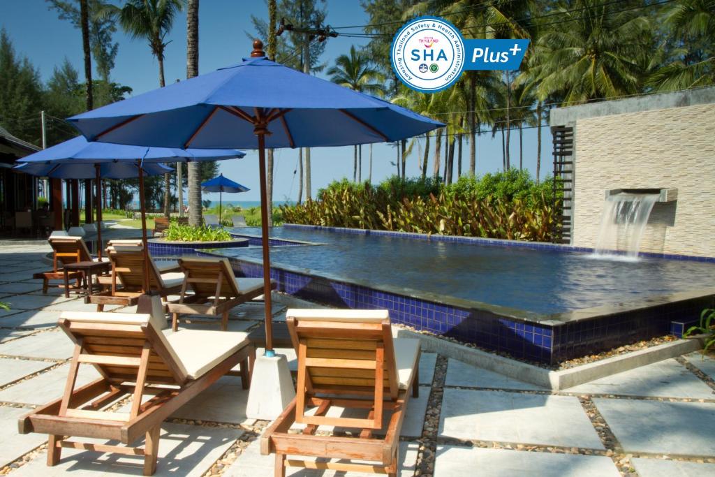 a pool with chairs and umbrellas next to a swimming pool at Khaolak Blue Lagoon Resort - SHA Extra Plus in Khao Lak