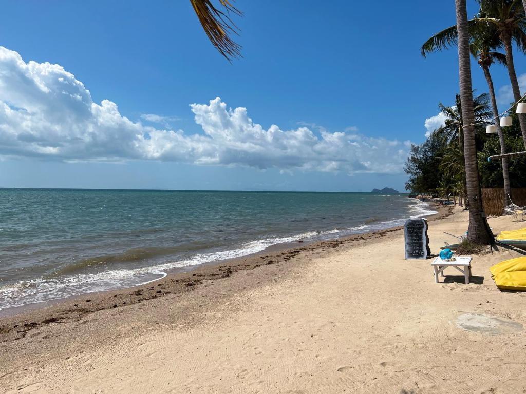 a sandy beach with palm trees and the ocean at Sea Love Beach Bar & Bungalows in Ban Tai