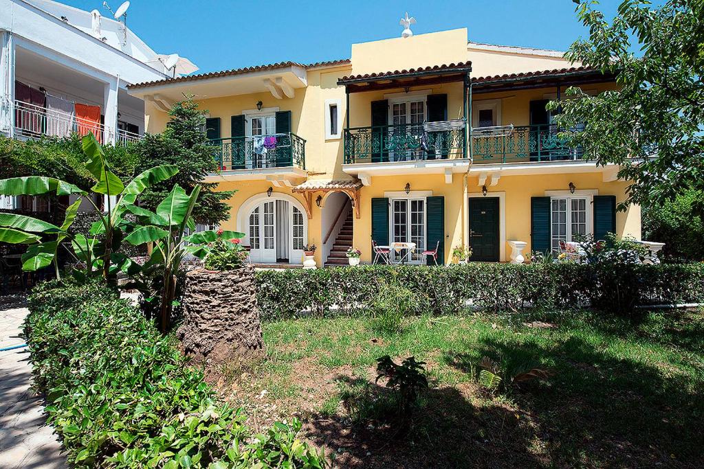 una casa gialla con balcone e cortile di Andreas Pool Complex a Città di Corfù