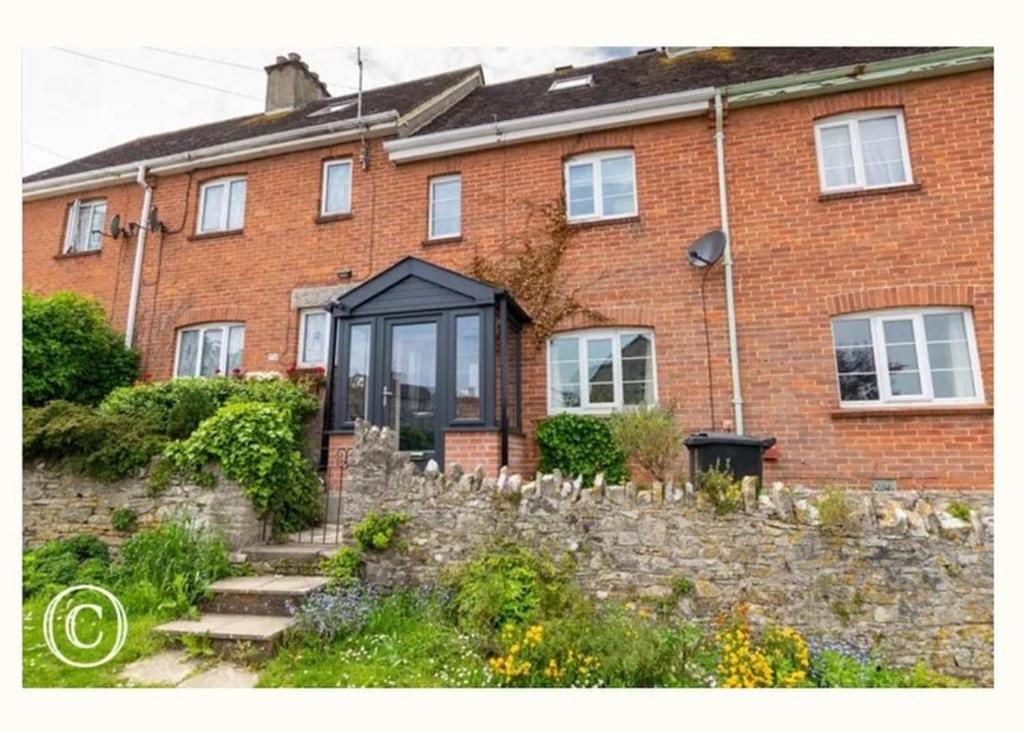 a brick house with a stone fence in front of it at Charming 3-Bed Cottage in Swanage in Swanage