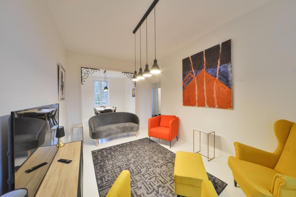 a living room with yellow and orange chairs and a table at La Maison d'Hestia in Vierzon