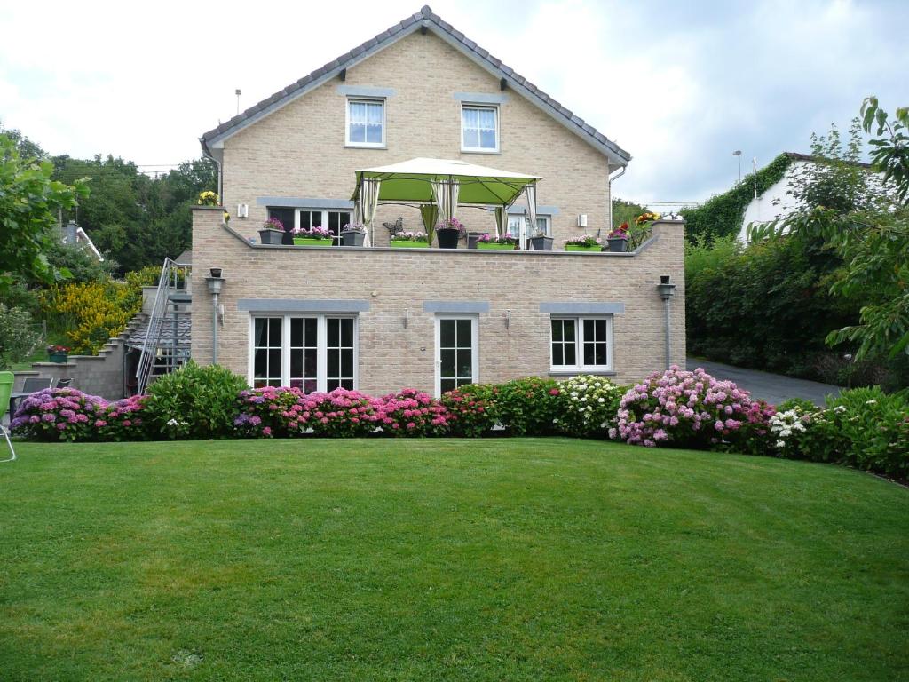 uma casa com uma varanda com flores num quintal em Ferienwohnung "Sweet Home" em Eupen