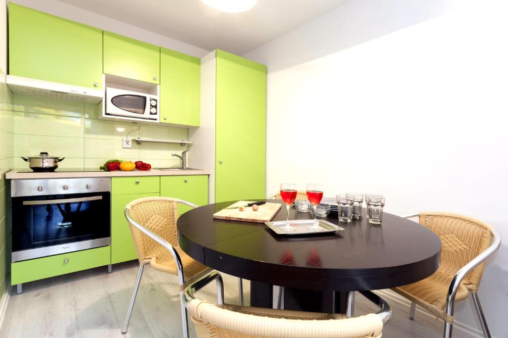 kuchnia z zielonymi szafkami i stołem z kieliszkami do wina w obiekcie APARTMENT Buena Vista Borik w Rovinj