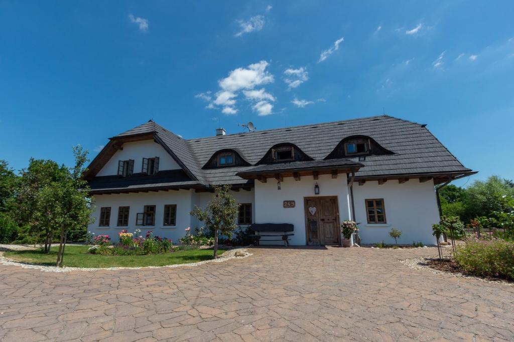 a white house with a black roof and a driveway at Apartmány NA DAŘILCE in Prostřední Libchavy