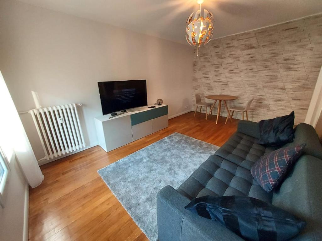 a living room with a couch and a tv and a table at Bel appartement 2 pièces, sortie de métro ligne 8 in Charenton-le-Pont